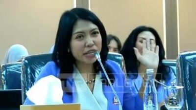 Ketua Umum HAKAN Analia Trisna mengenakan blazer biru sedang berbicara di depan mikrofon dalam RDPU bersama Komisi XIII DPR RI terkait revisi UU Kewarganegaraan