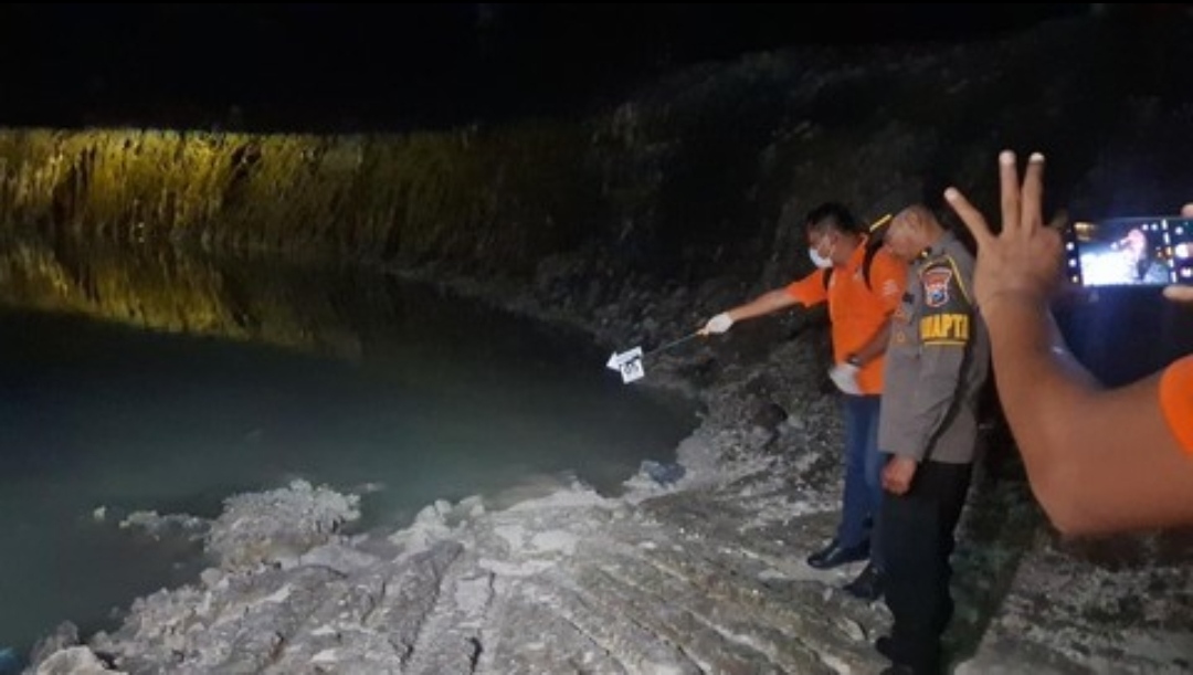 Petugas kepolisian dan tim evakuasi memeriksa tepian kolam bekas galian C yang gelap di malam hari, tempat enam santri ditemukan tewas tenggelam.