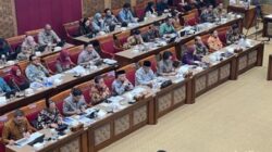 Sejumlah anggota Komisi X DPR dan jajaran Kemendikdasmen mengikuti rapat kerja di ruang rapat parlemen, dengan dokumen dan laptop terhampar di meja.