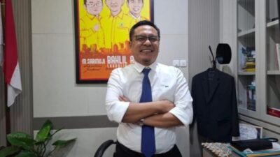 Wakil Ketua DPRD Surabaya dari Fraksi Golkar, Arif Fathoni, berdiri dengan tangan bersedekap di kantornya dengan latar belakang poster bergambar tokoh Partai Golkar dan bendera Merah Putih.