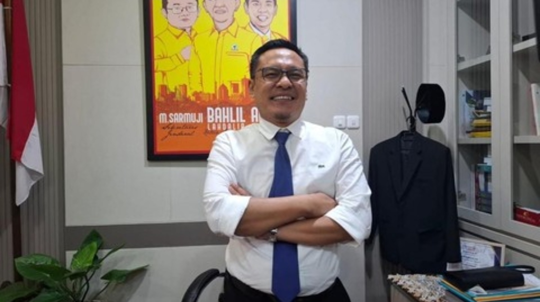 Wakil Ketua DPRD Surabaya dari Fraksi Golkar, Arif Fathoni, berdiri dengan tangan bersedekap di kantornya dengan latar belakang poster bergambar tokoh Partai Golkar dan bendera Merah Putih.