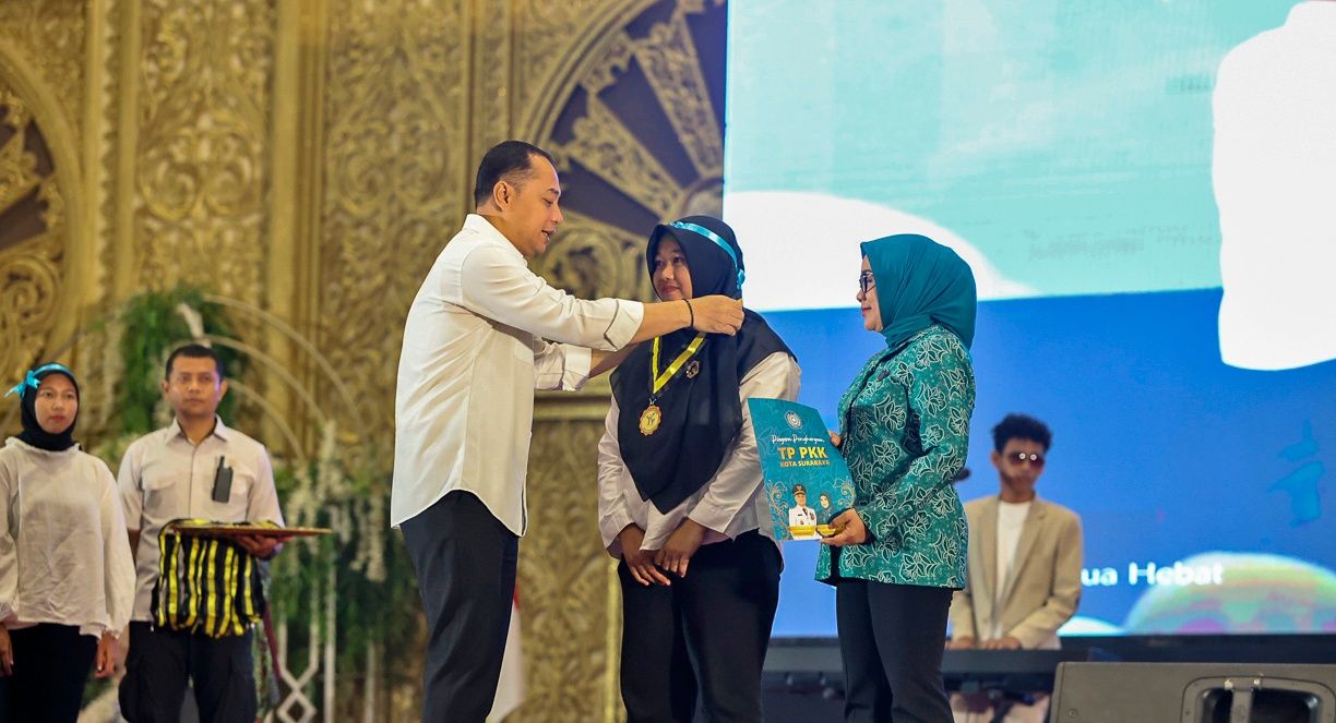 Wali Kota Surabaya Eri Cahyadi (kiri) sedang membenarkan tali medali wisuda salah satu peserta Sekolah Orang Tua Hebat (SOTH), didampingi oleh Ketua TP PKK Surabaya Rini Indriyani (kanan) yang menyerahkan sertifikat kelulusan di atas panggung Graha UNESA.