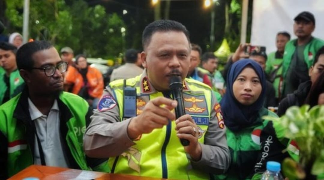 Kakorlantas Polri Irjen Pol Agus Suryonugroho berbicara menggunakan mikrofon saat duduk bersama sejumlah pengemudi ojek online yang mengenakan jaket hijau di sebuah warung kopi.