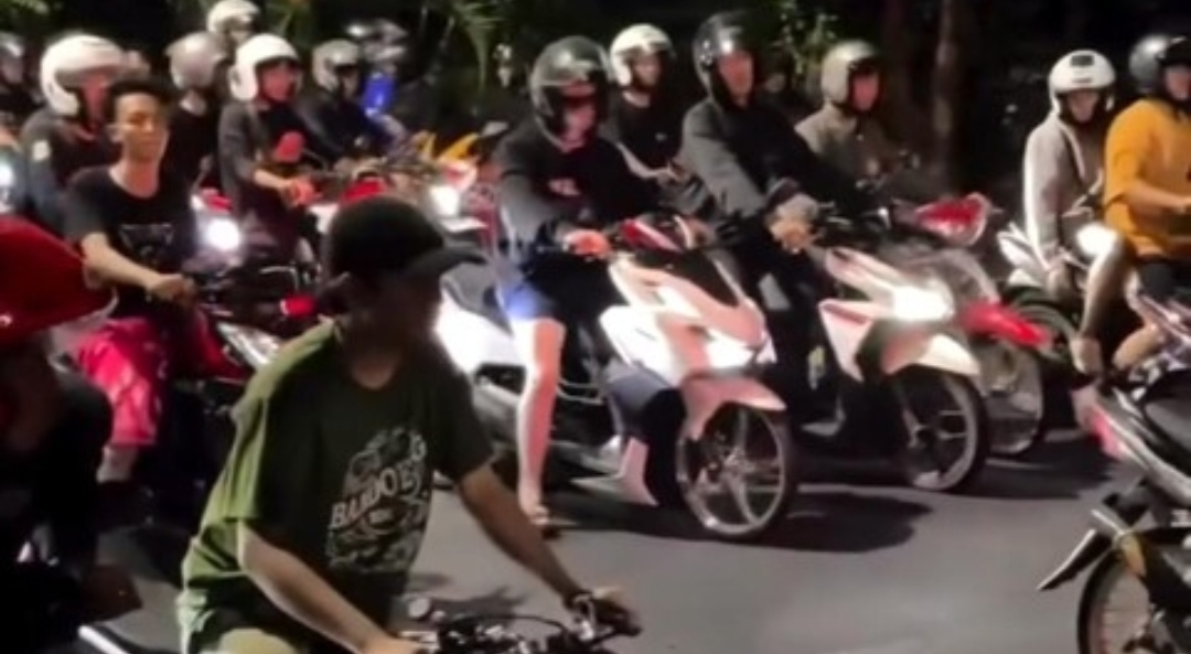 Sekelompok pemuda pengendara motor berkumpul memadati badan jalan pada malam hari, diduga hendak melakukan aksi balap liar di kawasan Jalan Panjang Jiwo, Surabaya, yang baru diaspal