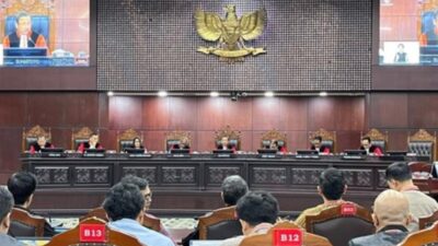 Suasana ruang sidang Mahkamah Konstitusi dengan deretan hakim duduk di meja persidangan dan peserta sidang terlihat dari belakang kursi pengunjung.