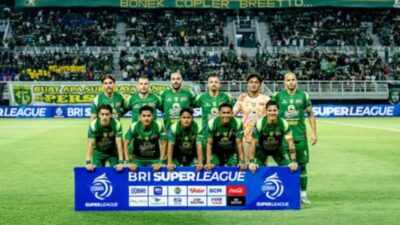 Satu tim kesebelasan Persebaya Surabaya berfoto bersama di lapangan sebelum pertandingan BRI Super League di Stadion Gelora Bung Tomo dengan latar belakang tribun penonton yang dipenuhi suporter Bonek.