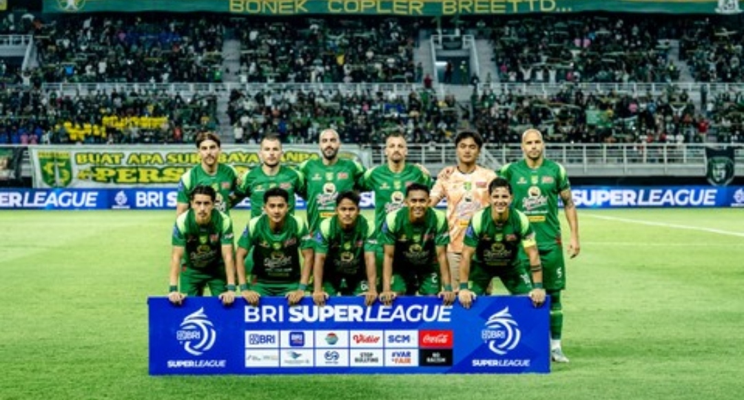 Satu tim kesebelasan Persebaya Surabaya berfoto bersama di lapangan sebelum pertandingan BRI Super League di Stadion Gelora Bung Tomo dengan latar belakang tribun penonton yang dipenuhi suporter Bonek.