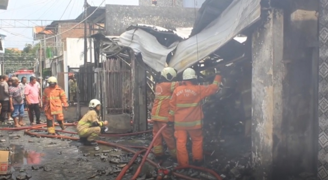 Petugas pemadam kebakaran memadamkan sisa api di gudang sparepart yang terbakar di Jalan Petemon 2A, Surabaya.