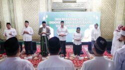 Wali Kota Surabaya Eri Cahyadi beserta istri dan para tokoh agama berdiri memanjatkan doa di depan panggung acara bertuliskan "Doa Bersama untuk Indonesia". Mereka tampak khusyuk berdoa di dalam ruangan berkarpet merah dengan latar dinding bernuansa emas.