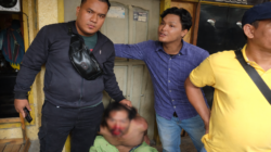 Seorang pria terduga pelaku pencurian sepeda motor tampak duduk di lantai dengan kondisi terluka, dikelilingi beberapa warga di depan bangunan kawasan permukiman.