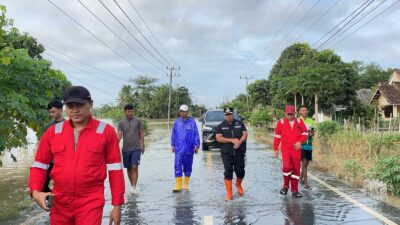 Petugas dan warga melintasi jalan tergenang banjir OKI