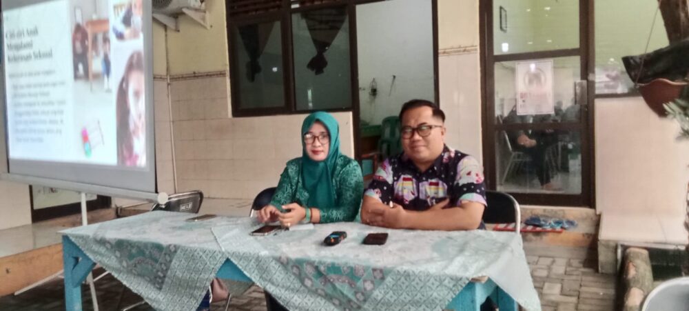 Lurah Bulak Banteng Matlilla dan Ketua TP PKK Aan Raivi duduk di depan layar materi saat memfasilitasi acara sosialisasi deteksi dini kekerasan terhadap ibu dan anak bersama akademisi UNAIR.