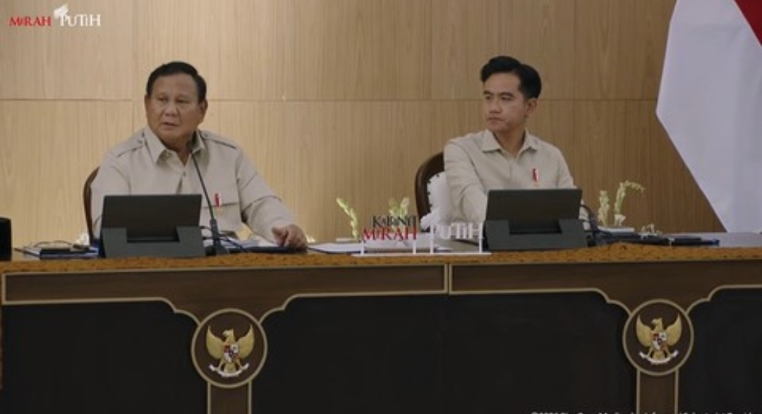 Presiden Prabowo Subianto memimpin rapat bersama jajaran pemerintah di ruang pertemuan resmi, dengan lambang Garuda Pancasila terlihat di bagian depan meja.