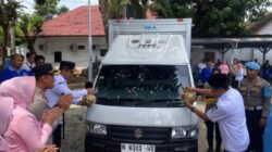 Kapolres Pasuruan Kota bersama pejabat menyiram kendi ke kendaraan boks berlogo SPPG saat prosesi peresmian, disaksikan peserta di sekitarnya.