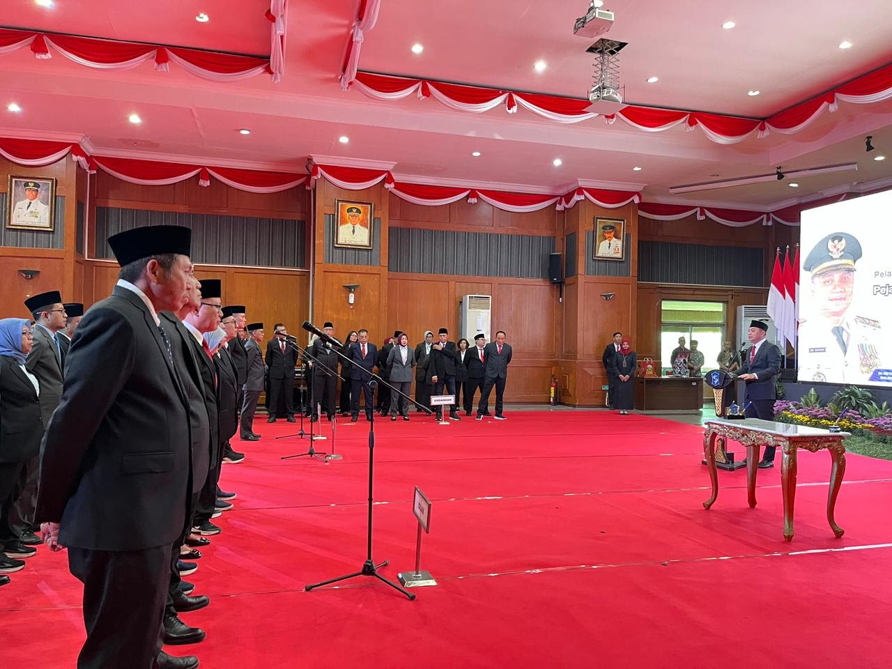 Wali Kota Surabaya Eri Cahyadi berdiri di podium memberikan sambutan di hadapan barisan pejabat yang baru dilantik di ruangan dengan dekorasi merah putih.